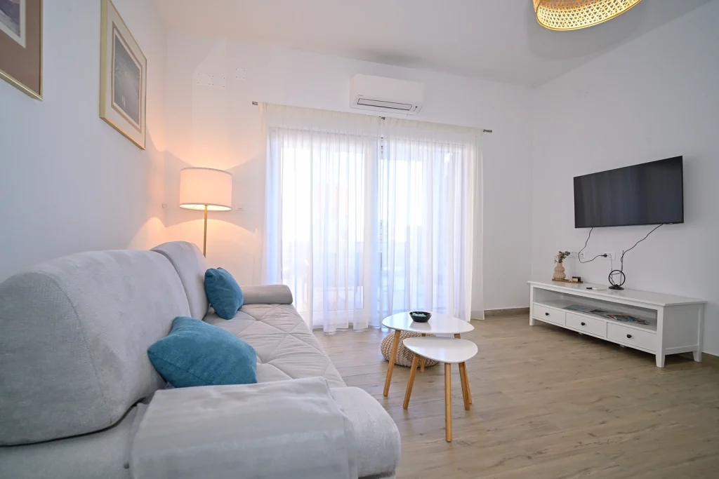 Svijetli dnevni boravak sa sofom, TV-om i klimom, apartman AMI Strožanac