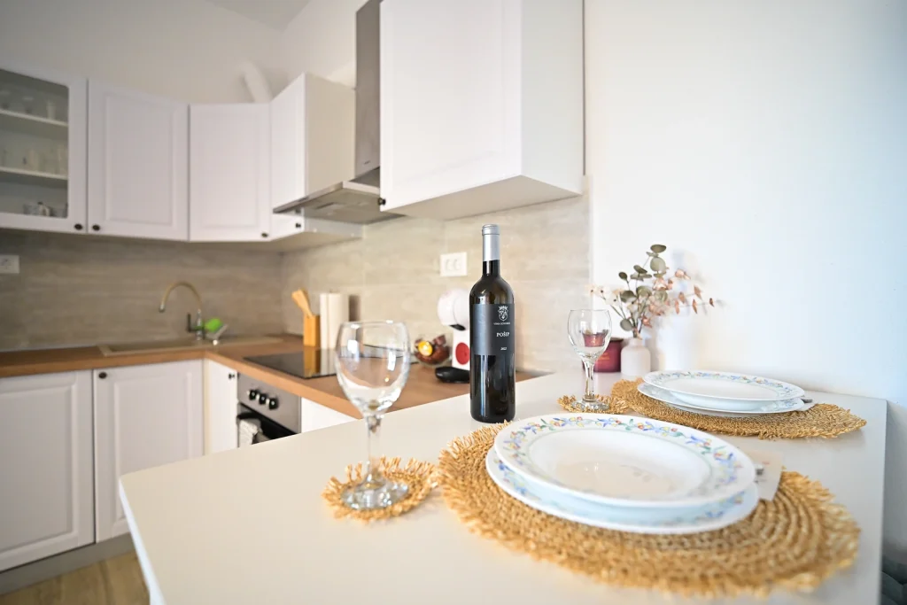 Radna površina kuhinje s vinom i čašama, apartman AMI Strožanac