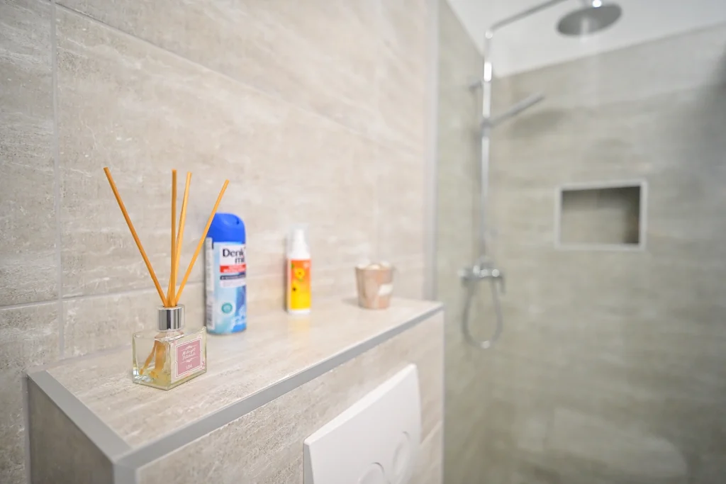 Detalj tuša s policom za toaletne potrepštine, kupaonica apartmana AMI Strožanac