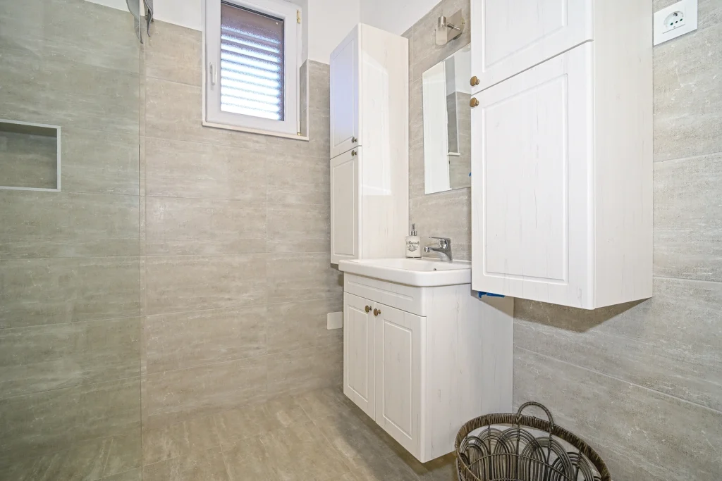 Umivaonik i visoki ormarić u kupaonici, apartman AMI Strožanac Podstrana