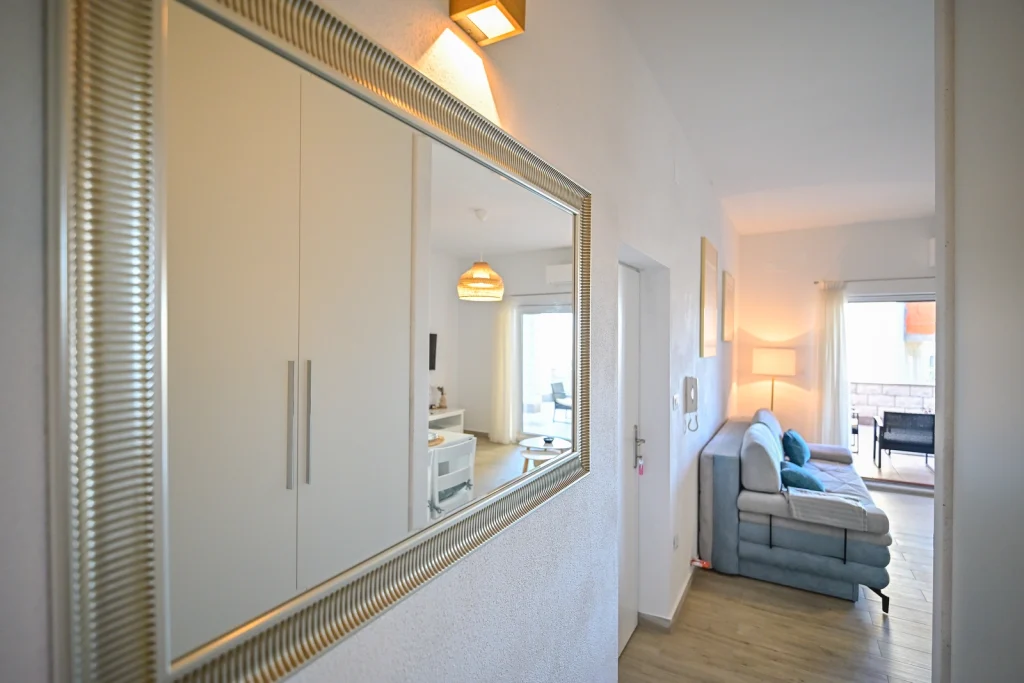 Predsoblje s ormarom i ogledalom te pogledom prema dnevnom boravku, apartman AMI Strožanac