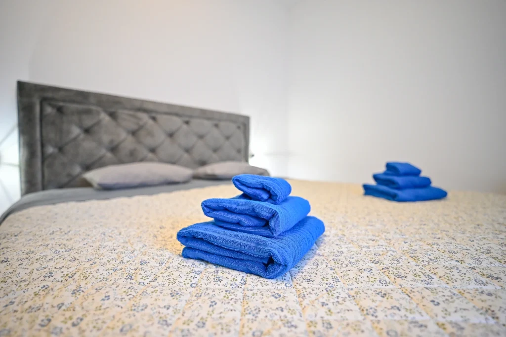 Bračni krevet s pripremljenim ručnicima, spavaća soba apartmana AMI Strožanac