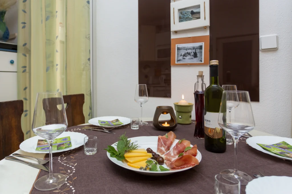 Blagovaonički stol s posluženim delicijama uz svijeće i vino u apartmanu Arca Strožanac