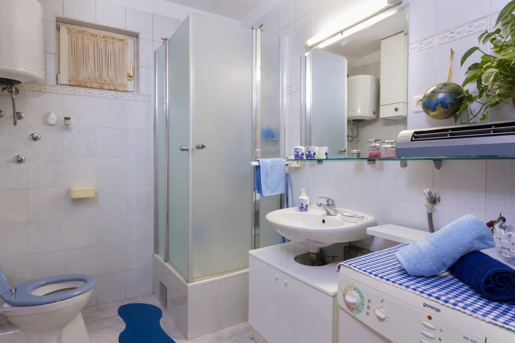 Kupaonica s tuš-kabinom, umivaonikom i WC-om u apartmanu Arca Strožanac