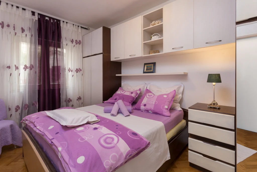 Spavaća soba s bračnim krevetom i ugradbenim ormarima u apartmanu Arca Strožanac