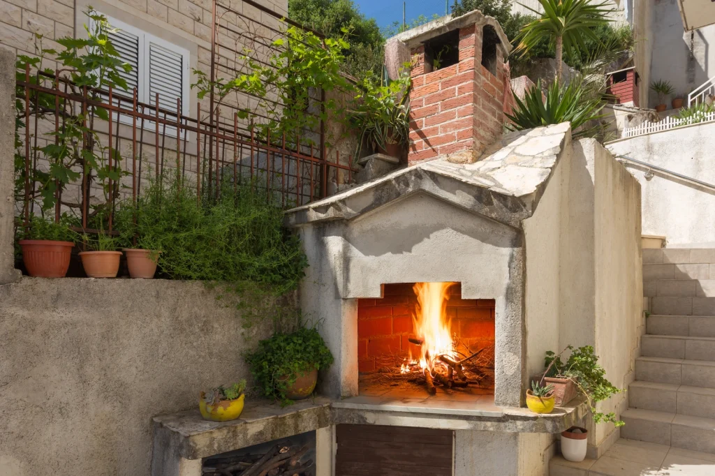 Vanjski kamin i roštilj na drva u dvorištu apartmana Arca Strožanac