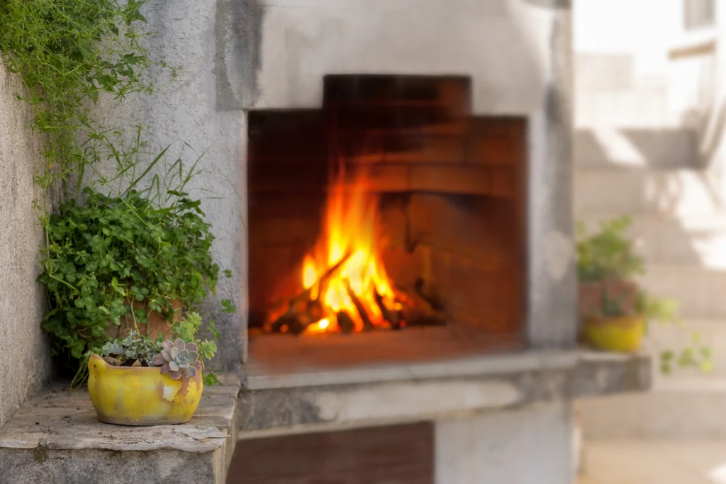 Zapaljeni vanjski kamin na drva za roštilj u apartmanu Arca u Strožancu