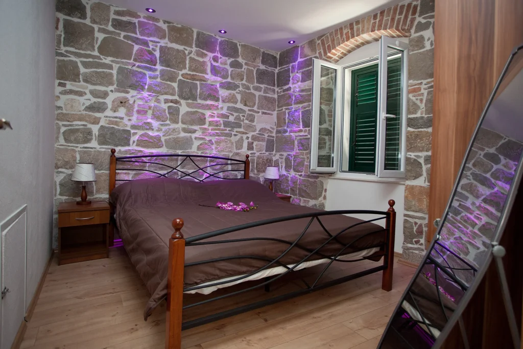 Spavaća soba s bračnim krevetom uz kameni zid, apartman Casa Matošića 3 Split