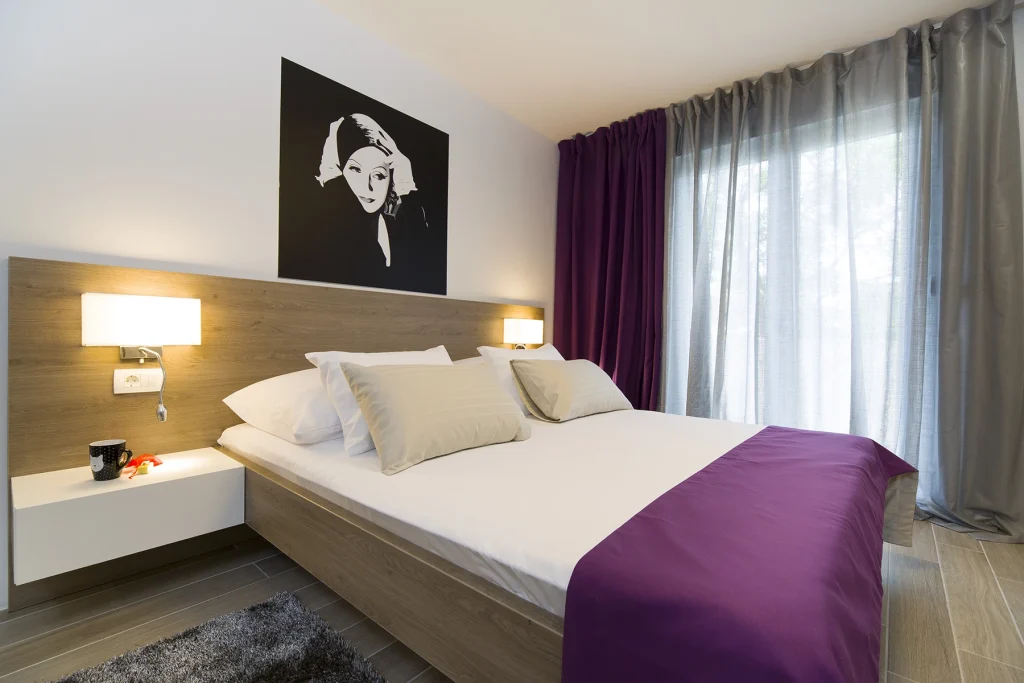Spavaća soba s bračnim krevetom i umjetničkim portretom, apartman Le Grey Split