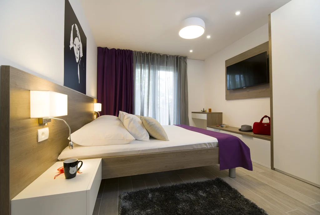 Spavaća soba s bračnim krevetom, TV-om i umjetničkim portretom, apartman Le Grey Split